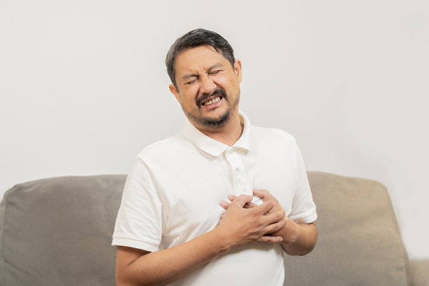 特写肖像照片，展示一位因胸痛而感到压力的男子，正用手触摸心脏部位。图片下载
