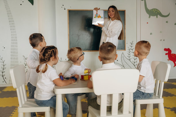 一位女性展示物品的图片。幼儿园的孩子们和他们的老师。图片下载