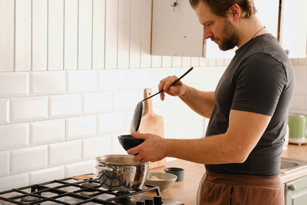 男子在家厨房的炉子上煮拉面。传统亚洲美食。特写照片展示男子的手在盛放配有新鲜蔬菜的意大利面。准备自制菜肴。图片下载