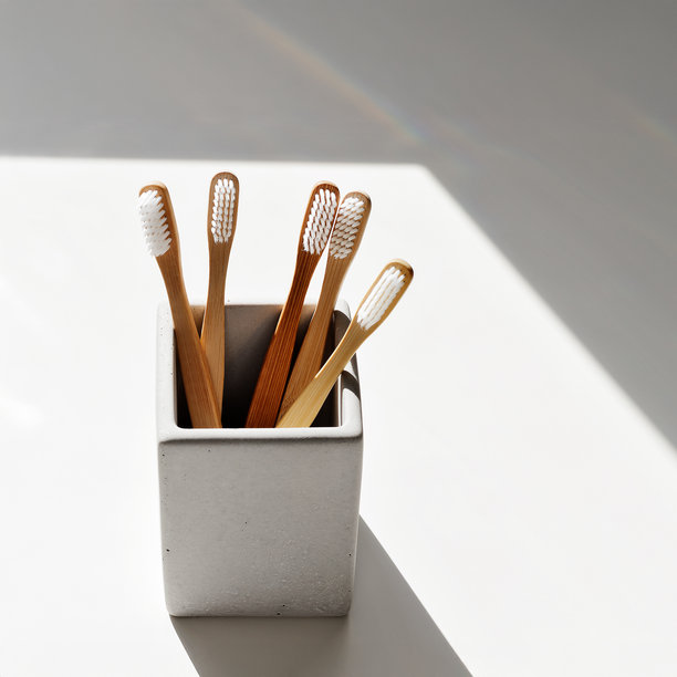 环保竹牙刷，白色刷毛，放置在方形灰色混凝土牙刷架中，阳光照射下伴有窗户投射的阴影。可持续生活理念，极简风格美学照片。图片下载