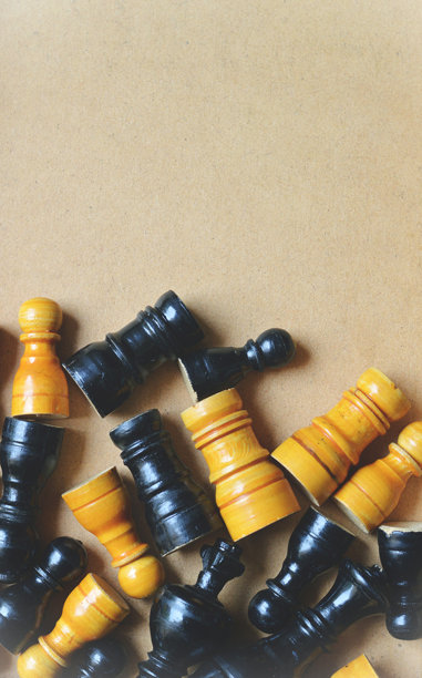 从上方俯视的垂直图片，展示了散落在米色纸板背景上的木制棋子，杂乱无序，周围有棕色纸张的留白空间。图片下载