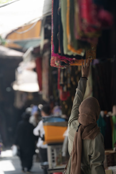 土耳其尚利乌尔法老市场中，身穿外套和头巾的穆斯林女性在购物的背影照片图片下载