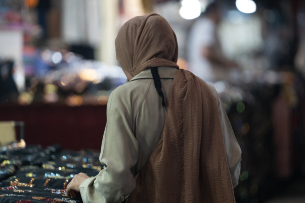 土耳其尚利乌法老市场上，身穿外套和头巾的穆斯林女性在购物的背影照片图片下载