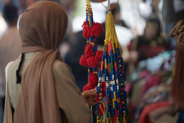 土耳其尚利乌尔法老市场中，身穿外套和头巾的穆斯林女性在购物的背影照片图片下载