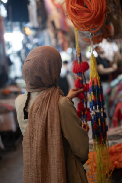 土耳其尚利乌尔法老市场中，身穿外套和头巾的穆斯林女性在购物的背影照片图片下载