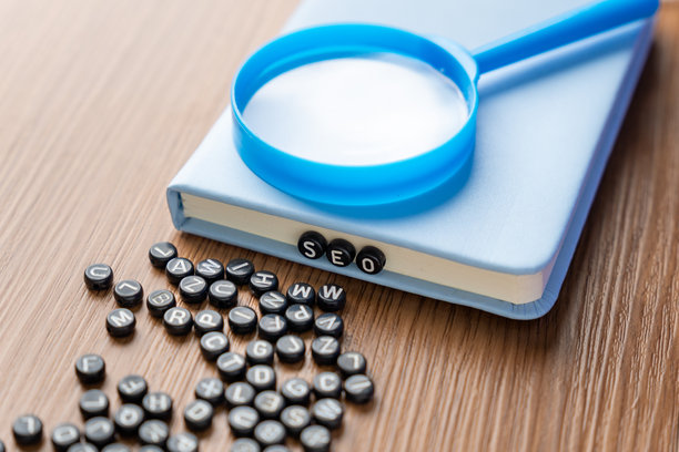 字母珠子拼写SEO，周围散落着更多珠子，放在木桌上。图片下载