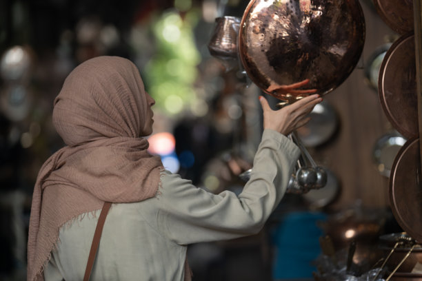 土耳其尚利乌尔法老市场中，身穿外套和头巾的穆斯林女性在购物的背影照片图片下载