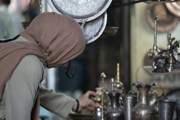 土耳其尚利乌尔法老市场中，身穿外套和头巾的穆斯林女性在购物的背影照片图片下载