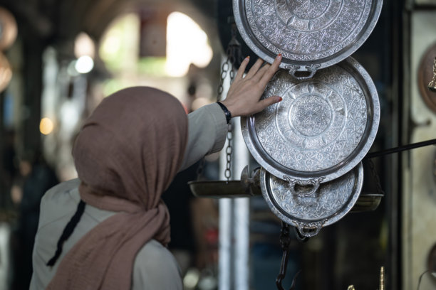 土耳其尚利乌尔法老市场中，身穿外套和头巾的穆斯林女性在购物的背影照片图片下载