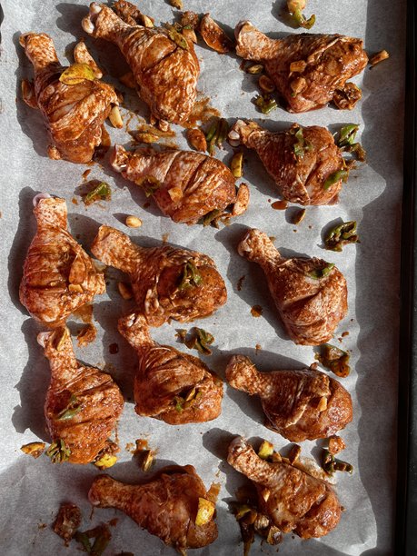 新鲜生腌制的鸡腿，侧面切割并划痕，准备放入烤箱，铺在烘焙纸上，俯视图（第二张照片）。图片下载