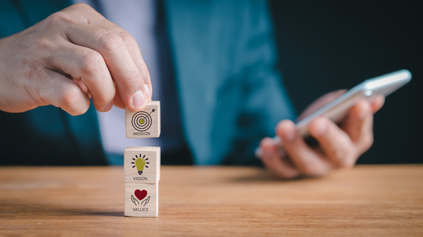 定义企业形象：一个人正在组装描绘使命声明、未来愿景和基本价值观的积木，这对商业成功和品牌完整性至关重要。图片下载