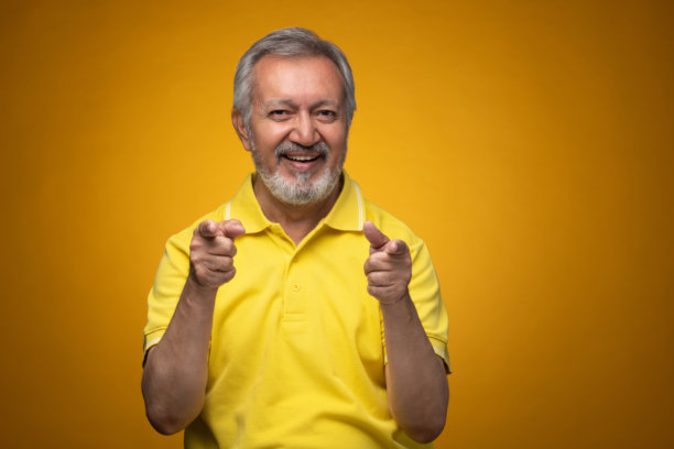 穿着黄色T恤的老年帅气男士肖像照片，背景为黄色。图片下载