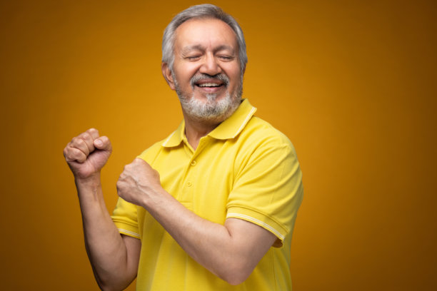 穿着黄色T恤的老年帅气男士肖像照片，背景为黄色。图片下载