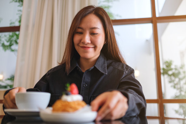 一位女性在咖啡馆里端着一盘草莓泡芙和咖啡的肖像照片图片下载