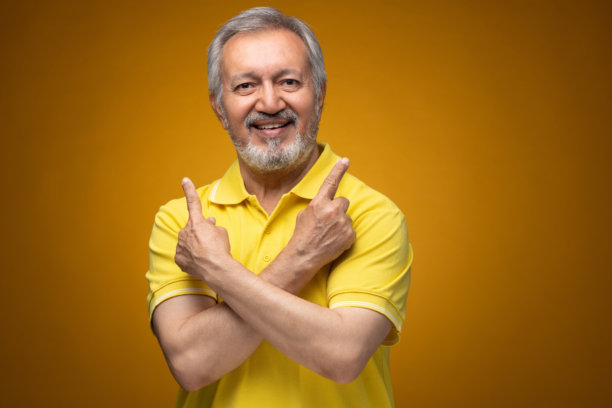 穿着黄色T恤的老年帅气男士肖像照片，背景为黄色。图片下载