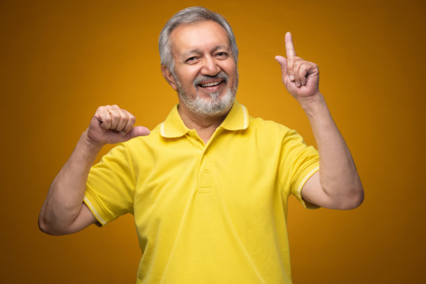 穿着黄色T恤的老年帅气男士肖像照片，背景为黄色。图片下载