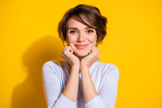 可爱女孩用手触摸脸颊的照片肖像，背景为明亮的黄色。图片下载