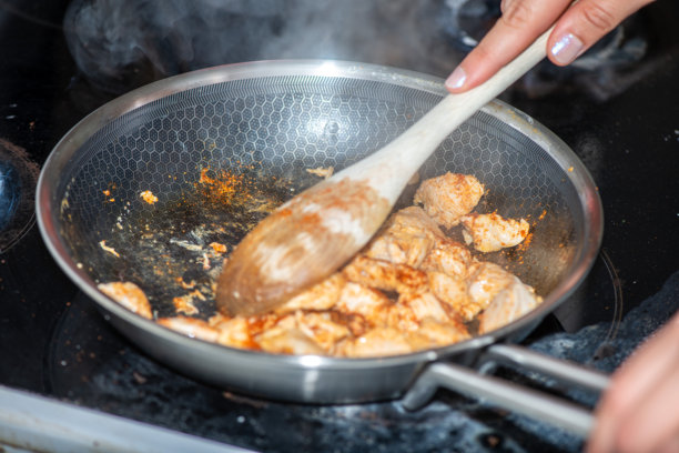 女人在烹饪鸡肉翻炒的特写照片图片下载