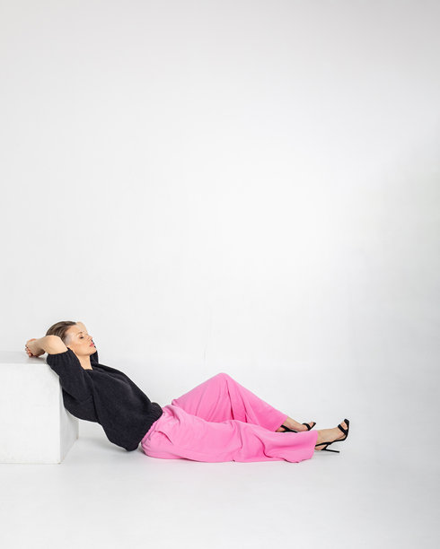 模特外貌的美丽女性肖像。女孩穿着黑色毛衣和粉色裤子，背景为灰色。时尚妆容的漂亮女性在摄影棚中摆姿势。竖版照片图片下载