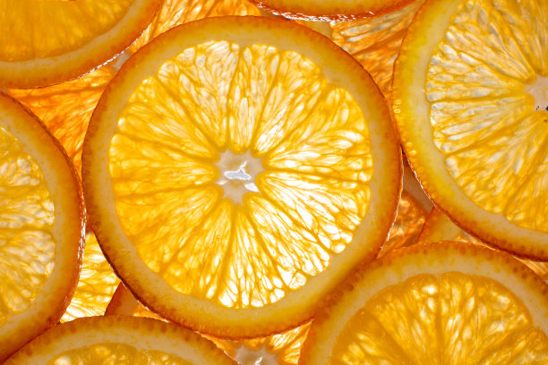 照片展示了一个切开的橙子的表面细节，背后有工作室灯光照射。图片下载