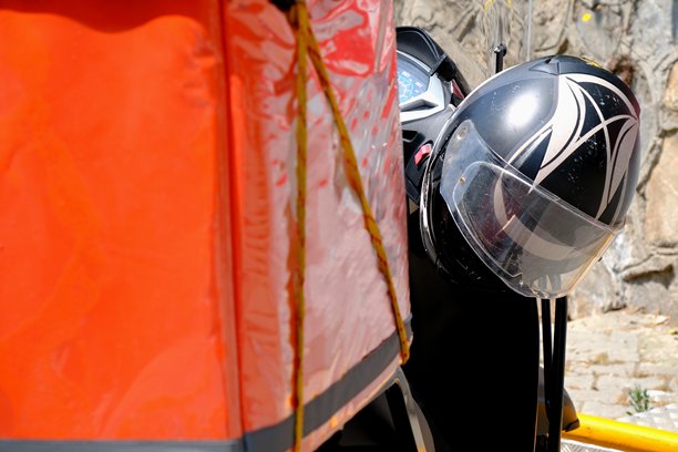 摩托车快递员将快速包裹送到家中，以及摩托车头盔的特写照片。图片下载