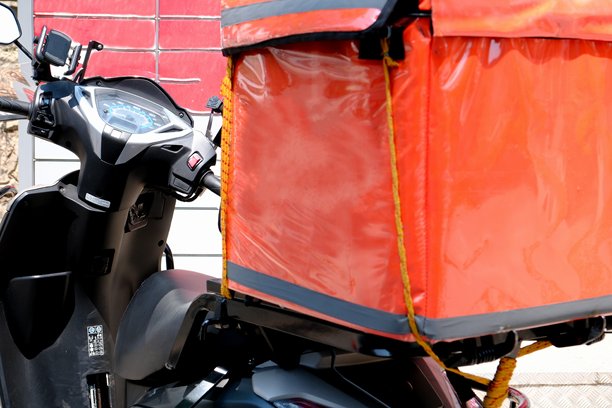 摩托车快递员为家庭送达快速包裹，以及摩托车头盔的特写照片。图片下载