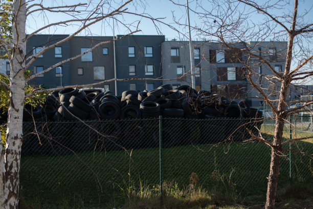 城市景观照片，展示了住宅建筑前的一堆轮胎，突显现代工业区的环境挑战和回收潜力。图片下载
