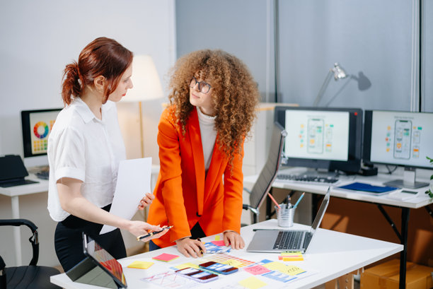 两位女性设计师在现代办公室中头脑风暴色彩方案。创意团队合作、品牌塑造和用户界面用户体验。图片下载