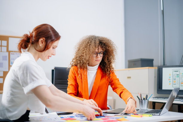 两位女性设计师在现代办公室中头脑风暴色彩方案。创意团队合作、品牌塑造和用户界面用户体验。图片下载