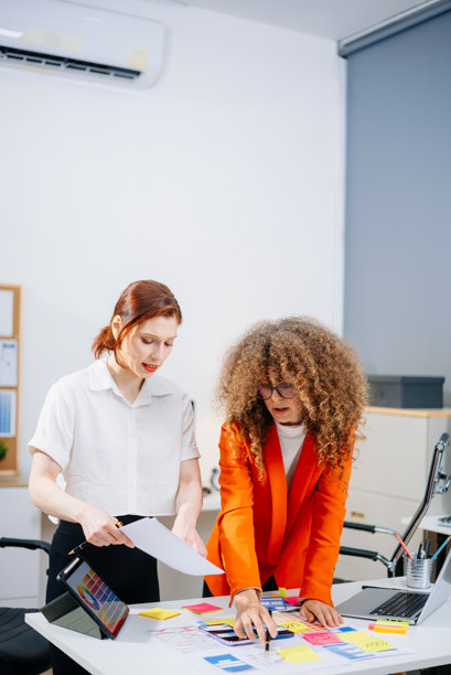 两位女性设计师在现代办公室中头脑风暴色彩方案。创意团队合作、品牌塑造和用户界面用户体验。图片下载