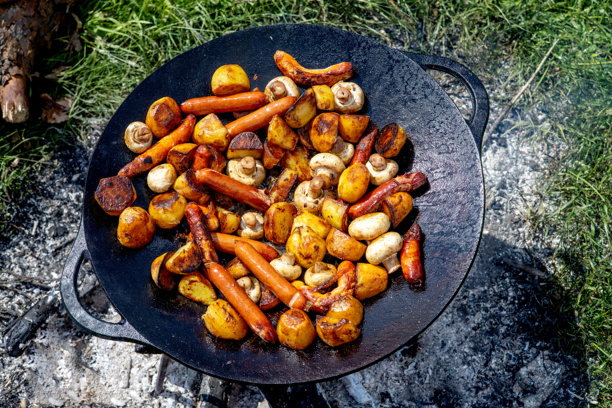 香菇、烤香肠和铸铁平底锅上烹饪的土豆。夏季自然中的野餐。食物的横向照片。图片下载