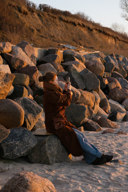 女人用手机拍摄海洋的照片。图片下载