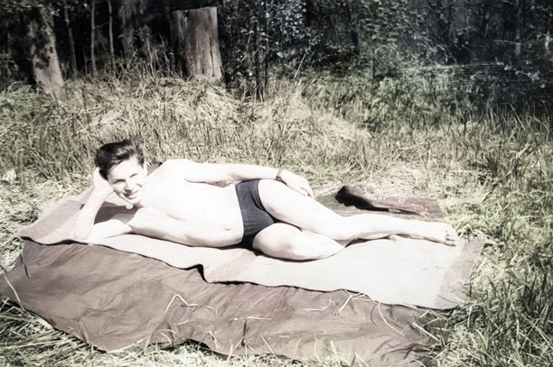 年轻男子在森林中沐浴阳光的复古肖像。1962年的老照片。图片下载