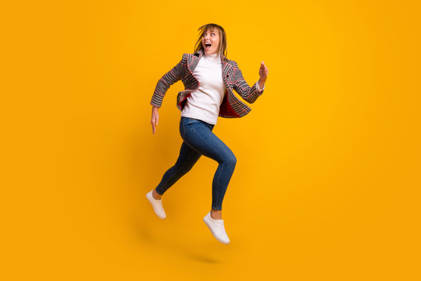 满脸惊讶的年轻女孩的全身侧面照片，张嘴看起来很感兴趣，背景为黄色的空白空间。图片下载