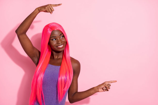 非洲裔美国女性在粉色背景上用两根手指指向空白处的照片肖像图片下载