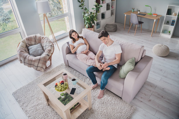 俯视角度的照片，温柔的丈夫为妻子按摩脚趾，和谐的好心情，愉快的周末室内时光。图片下载