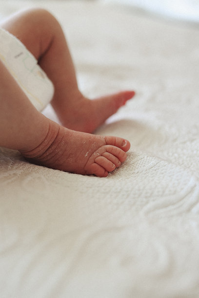 新生儿小脚丫特写，放在柔软的绗缝毯上。非常适合婴儿护理产品、孕妇品牌、尿布广告、育儿博客和儿童健康宣传活动的图片。图片下载