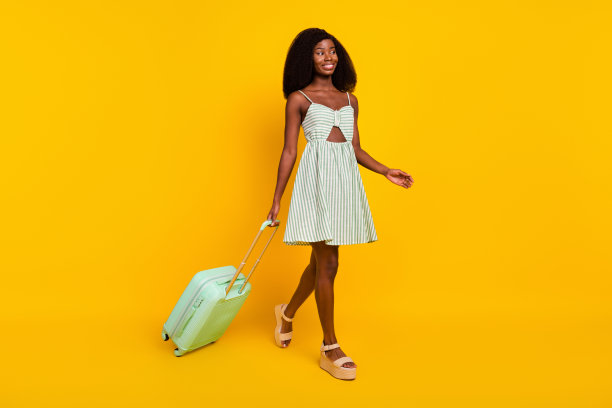 年轻黑人女孩在黄色背景下走向飞机行李托运处的全身侧面照片图片下载