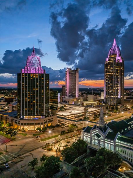 阿拉巴马州莫比尔市黄昏时分的天际线鸟瞰图，灯光璀璨的摩天大楼与戏剧性的云彩。图片下载