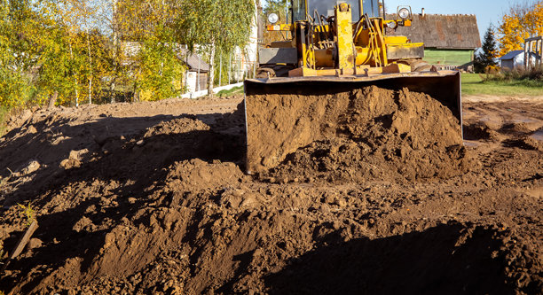 建筑工地上的黄色推土机。侧面视图的大轮挖掘机正在平整和清理土地。移动土方。留白空间。建筑区域。特种运输。高质量照片。图片下载