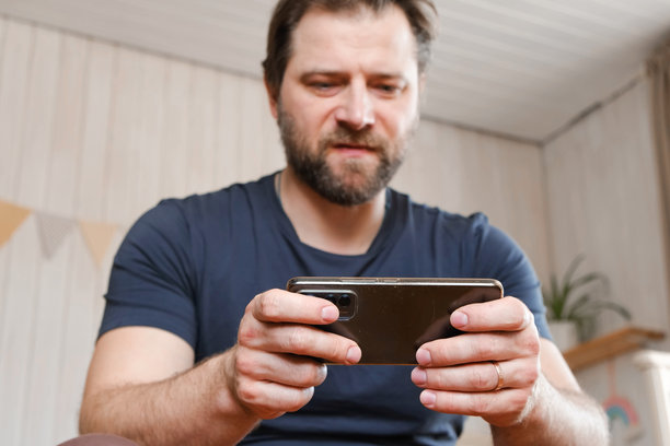 男子在家中使用手机。帅气的男士在浏览社交网络、玩游戏、网上购物、与朋友聊天、写或阅读信息。特写镜头。4K视频素材。图片下载