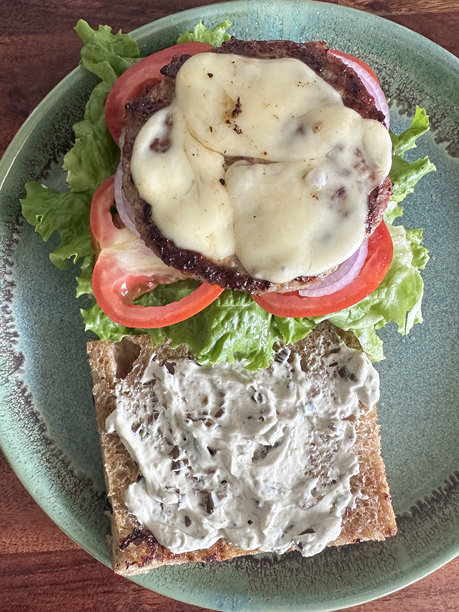 牛肉芝士汉堡三明治的俯视照片，包含肉饼、生菜、西红柿、红洋葱和芝士。图片下载