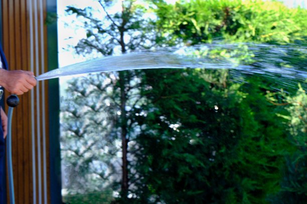 男性手部特写和全景照片，使用水管给花园浇水。图片下载