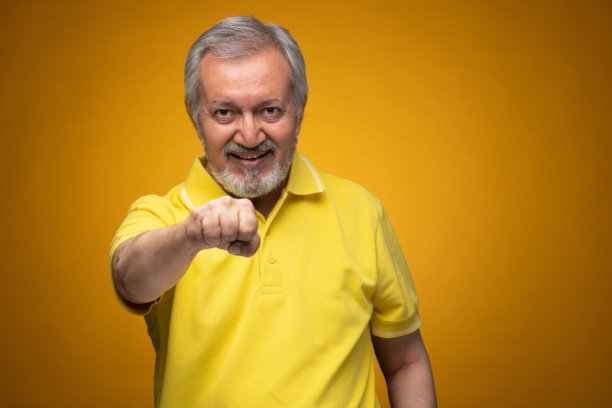 穿着黄色T恤的老年帅气男士肖像照片，背景为黄色。图片下载