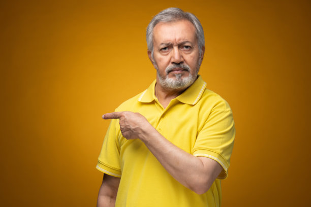 穿着黄色T恤的老年帅气男士肖像照片，背景为黄色。图片下载