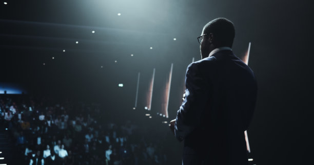 非洲商人在国际商业会议上发表全球经济战略演讲。公众演讲者分享专业知识和领导见解。背影照片。图片下载