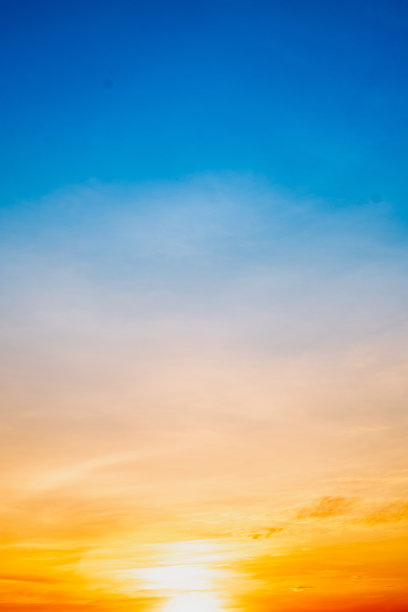 美丽的日落景观，奢华柔和的渐变橙金色云彩和阳光映照在蓝色戏剧性的天空中，完美适合作为背景，早晨、傍晚、黄昏，气候变化，垂直日落照片图片下载