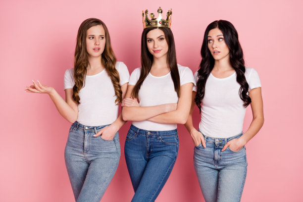 三位年轻女孩的照片，其中一位戴着金色王冠，表情不悦，身边的朋友显得消极，背景为粉色。图片下载