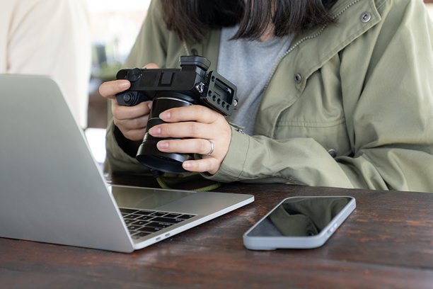 年轻女性将照片从数码相机传输到笔记本电脑，进行创意工作流程和媒体备份图片下载