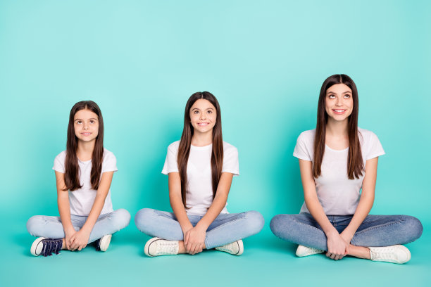 三姐妹坐在莲花坐姿中，微笑着仰望，背景为鲜艳的蓝色，展现全身的照片。图片下载